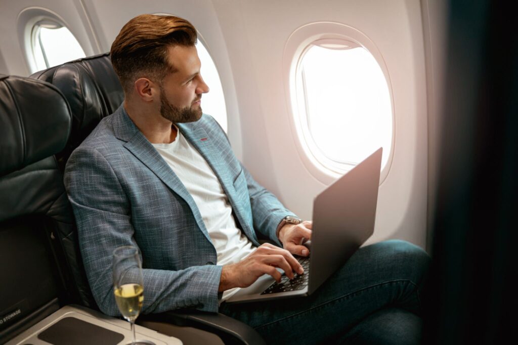 Male passenger working on laptop in airplane 1024x682
